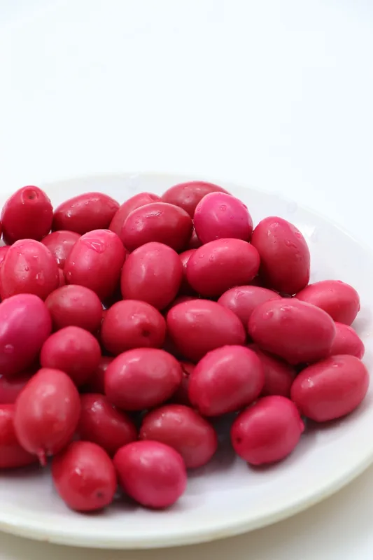 Beyaz tabakta pembe zeytinler, beyaz fon